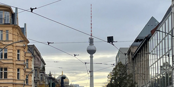Foto einer Straße mit dem Beriner Fernsehturm im Hintergrund.