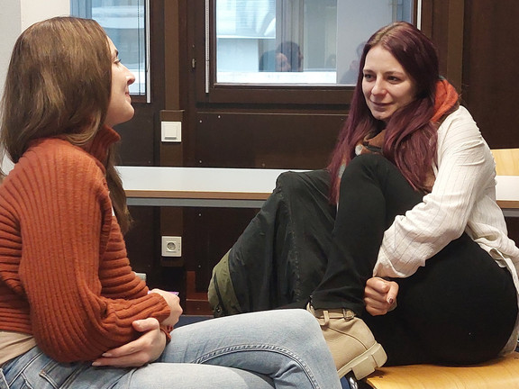 Zwei Personen, die sich gegenüber sitzen und sich miteinander unterhalten.