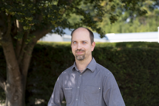 Carsten Bender schaut frontal in die Kamera. Im Hintergrund: ein Baum und eine Hecke.