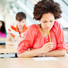 Female student at exam, bent over leaf in pensive pose