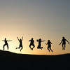 6 people jumping on a ountain with the sunset behind them