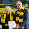 Two men with BVB scarves hold a certificate in their hands.