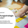 Foto mit Text: Das Foto zeigt Hände, die bunte Post-It-Zettel auf einem Plakat arrangieren. In einem weißen Kreis steht folgender Text: "2. Phase gestartet! Forschungsstrategie 2023-2027, Unsere Themen: Diversität, Lehre, Exzellente Wissenschaftler*innen, Transfer, Wissenschaftskommunikation" 