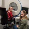 A girl sits on a chair and a woman sits next to her. Both are looking at the camera.