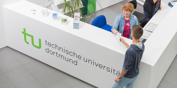 Ein Student gibt seine Wartenummer bei der Studienberatung ab.