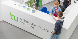 Ein Student gibt seine Wartenummer bei der Studienberatung ab.