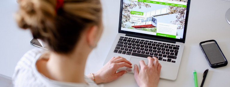 Arbeit am Laptop Am Schreibtisch sitzende Studentin tippt auf dem Laptop, daneben liegen Bücher und Stifte.