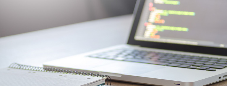 Laptop and notebook on a desk.